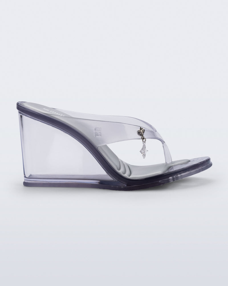 Side view of a clear grey Nabeela wedge flip flop with star charm on the strap