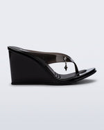 Side view of a black Nabeela wedge flip flop with star charm on strap