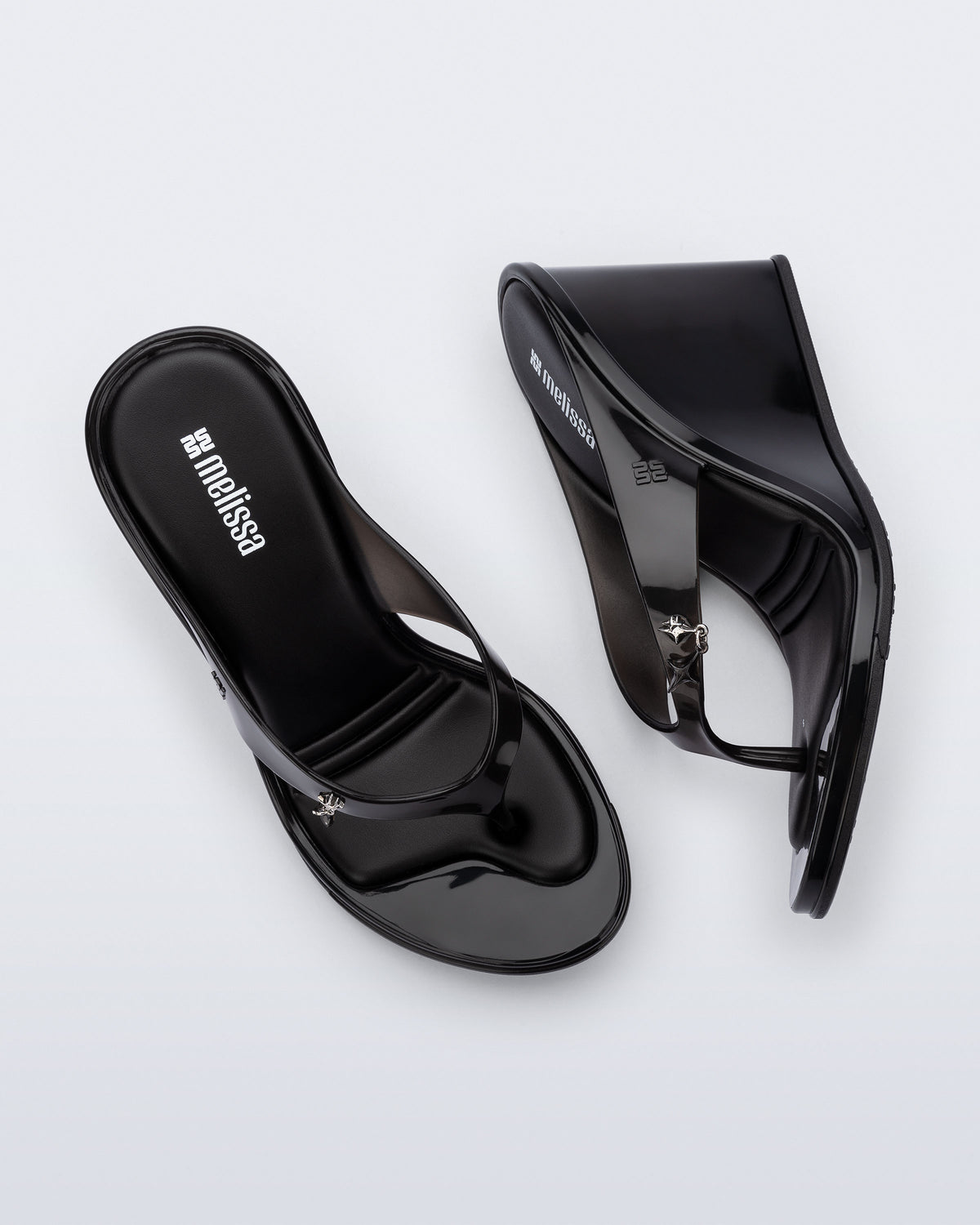 Top and side view of a pair of black Nabeela wedge flip flops with star charm on strap