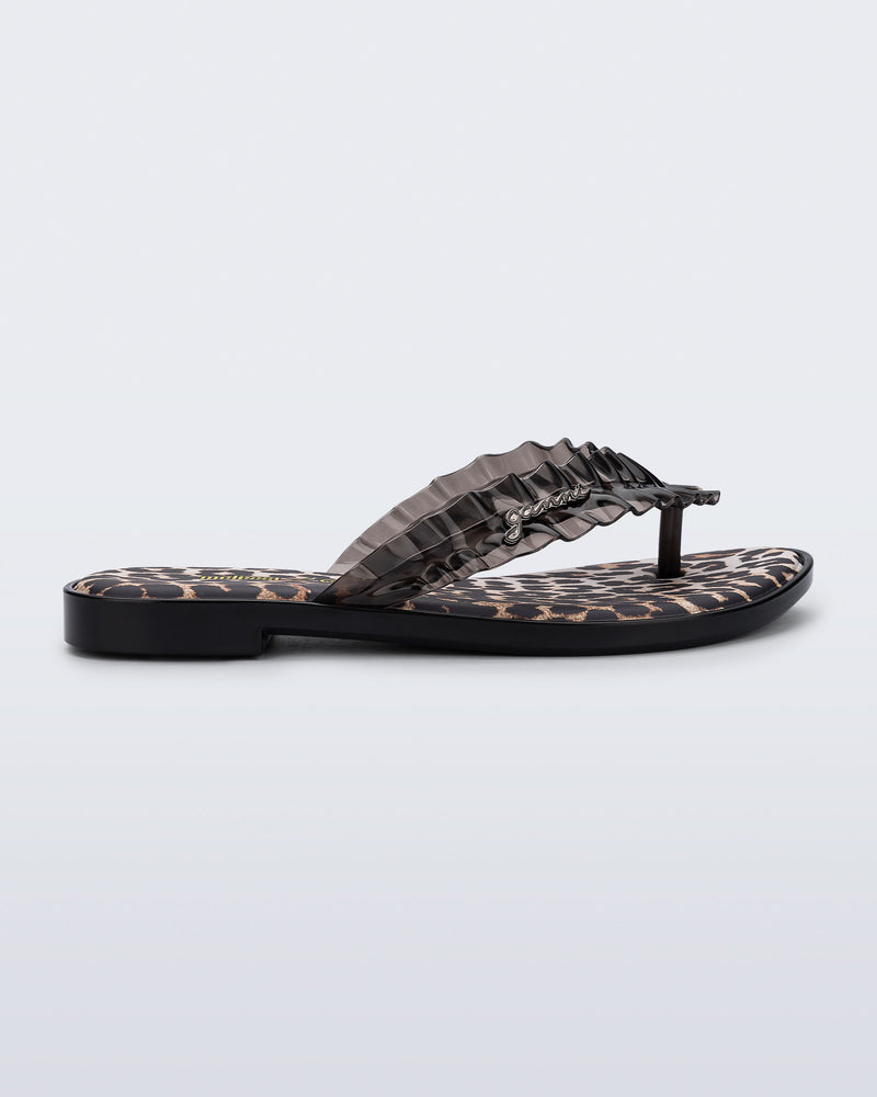 Side view of a black Flip Flop Slim+ GANNI sandals with leopard print foot bed and faux ruffle strap