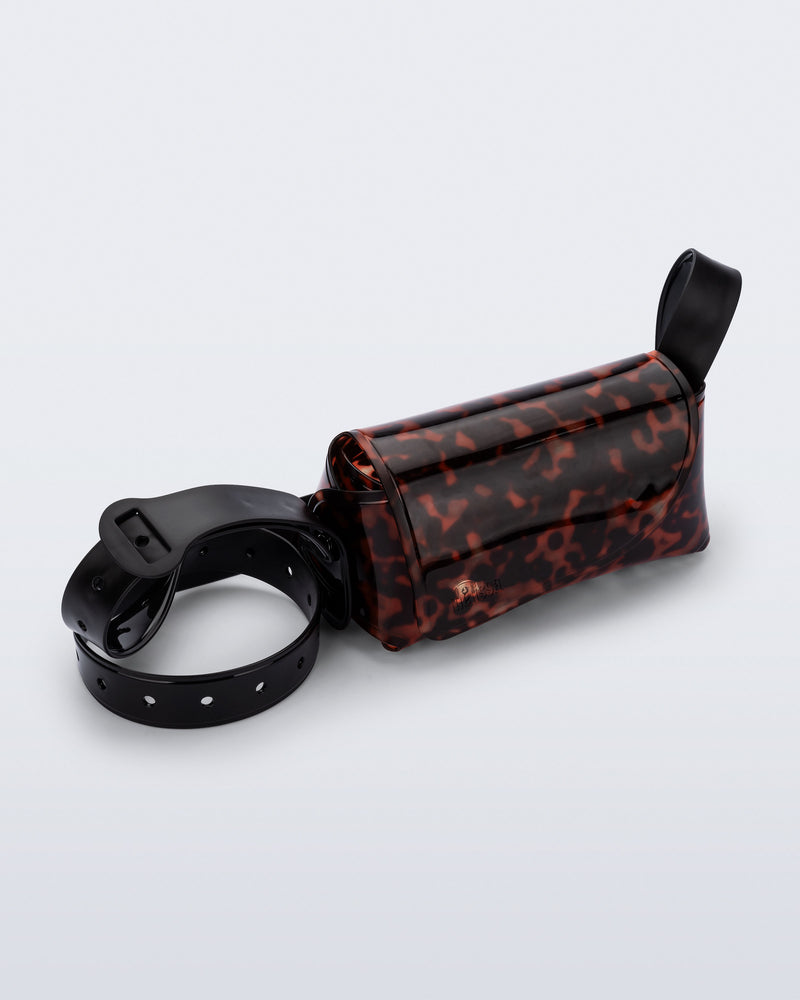 Angled view of a tortoise Cross Bag with adjustable black strap