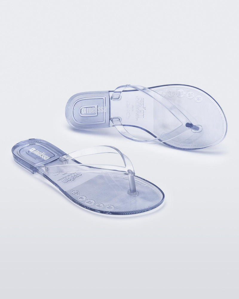 Angled and top view of a pair of clear Harmonic Jelly flip flops