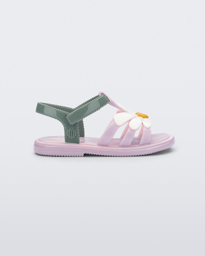 Side view of a pink Hip Bloom baby sandal with white flower and green ankle strap
