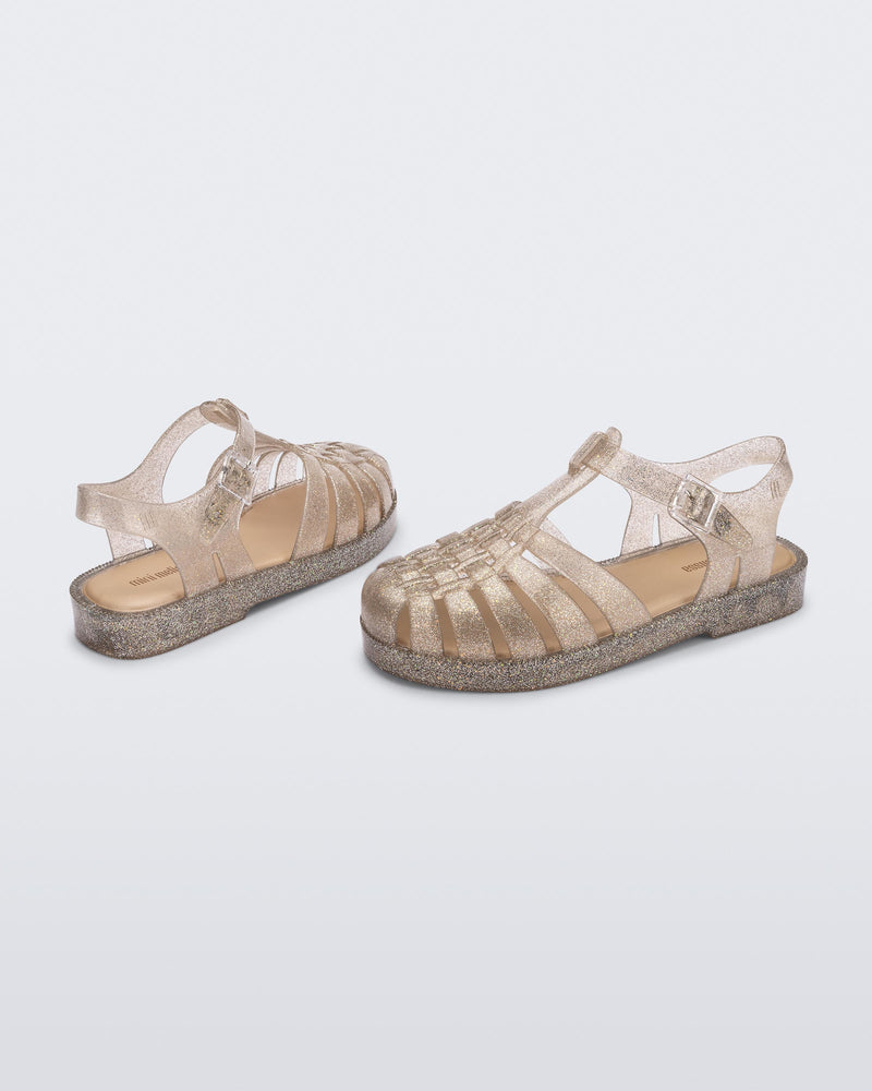 Top and angled view of a pair of glitter beige kids Possession sandals
