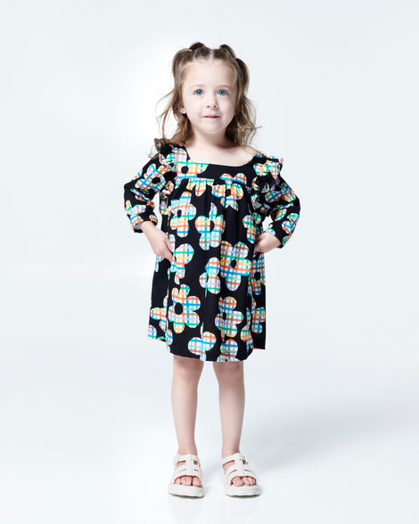 Model in black flower dress wearing a pair of beige Ella baby sandals
