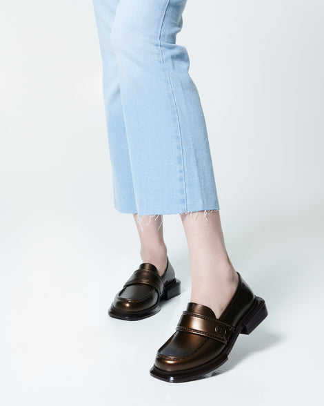 Model's legs in ankle jeans wearing a pair of bronze Spencer loafers