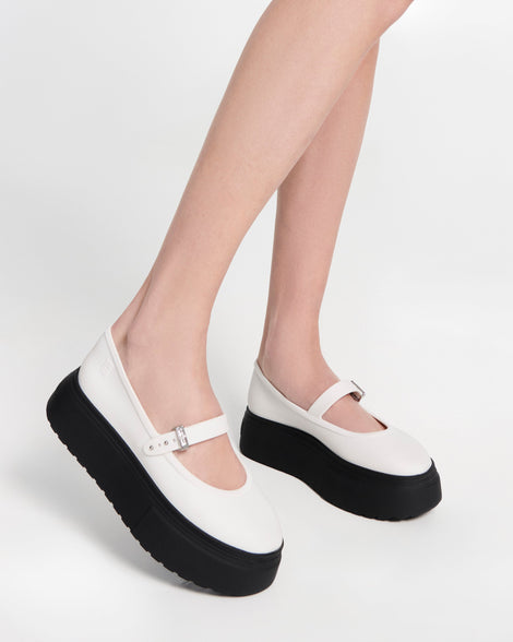 Model's lets in a pair of white Soft Ballerina Platform flats with black soles