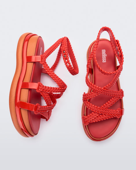 A top and side view of a pair of red Melissa Buzios platform sandals with multiple textured straps that mimic sisal braids across the front of the shoe as well as an ankle strap