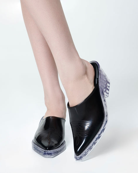 Model's legs wearing a pair of black with clear heel Texas Mule heels