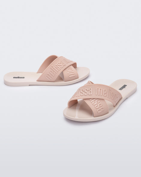 Side and angled view of a pair of beige M Lover adult slides