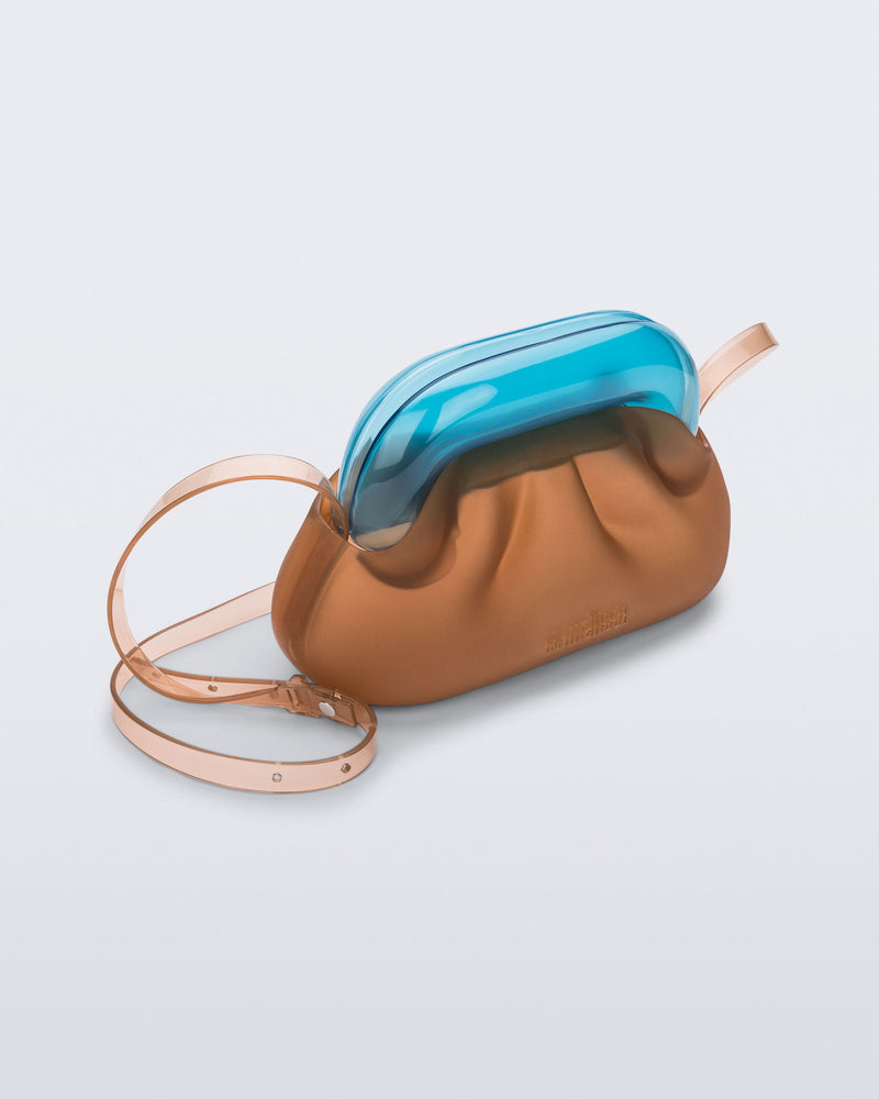 Angled view of a small clear orange bag with blue clutch and long strap