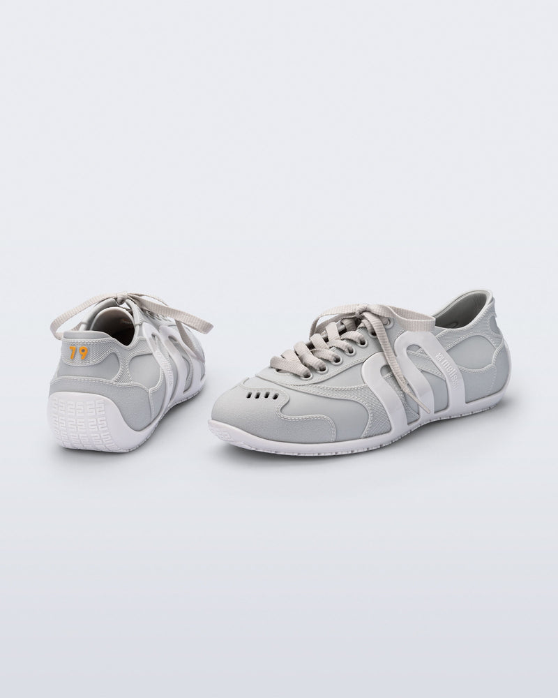 Back and side view of a pair of grey Motion sneakers with white colored sole and M monogram on side and 79 on heel