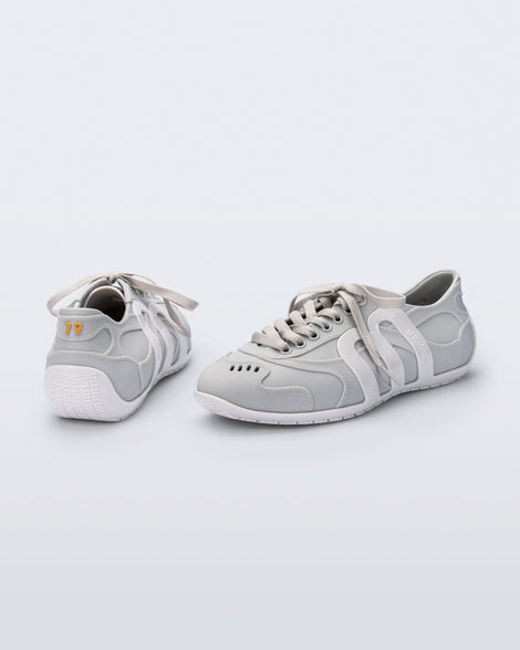 Back and side view of a pair of grey Motion sneakers with white colored sole and M monogram on side and 79 on heel