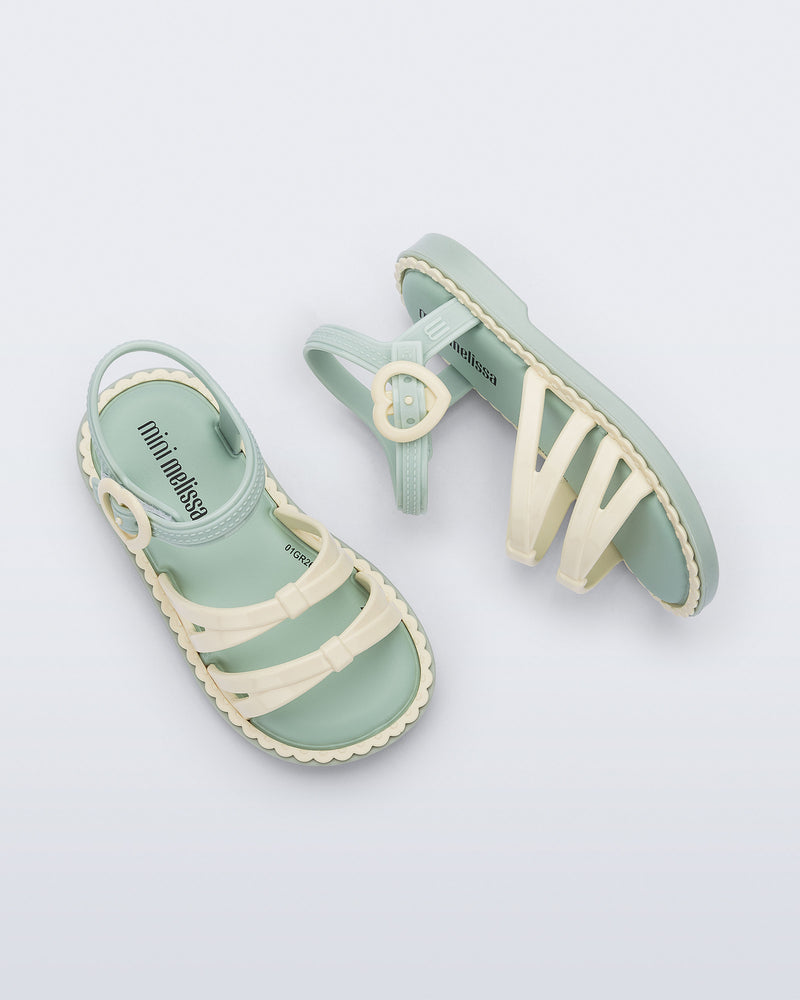Side and top view of a pair of green Aurora baby sandals with beige trim, straps and buckle