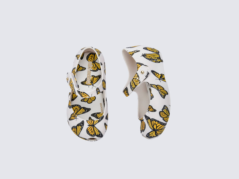 Top and side view of a pair of white Ultragirl Print baby ballerinas with orange and black butterflies
