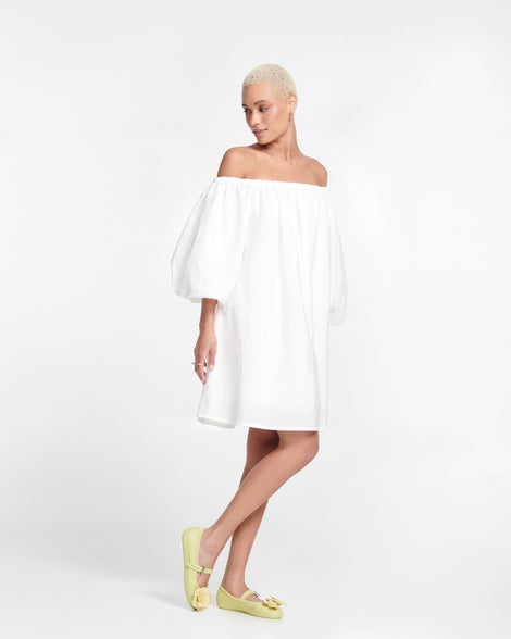 Model in a white dress wearing a pair of green Soft Ballerina Petals flats