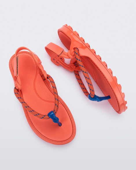 Top and side view of a pair of orange Bond sandals with textile strap and blue toe piece