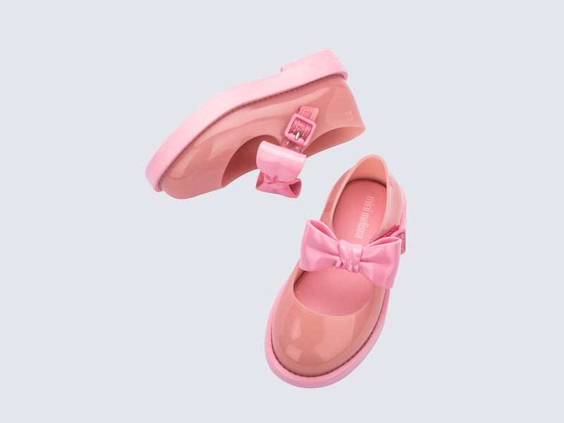 Top and side view of a pair of pink Blair baby mary janes with bow in the strap