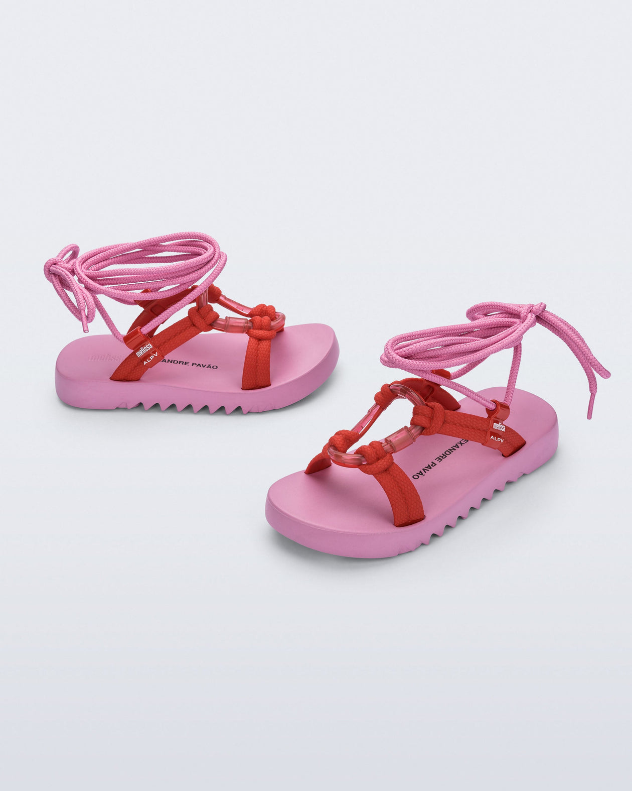 Side and angled view of a pair of pink sole, red upper, and pink ankle strap Kirk + Alexandre Pavao sandals