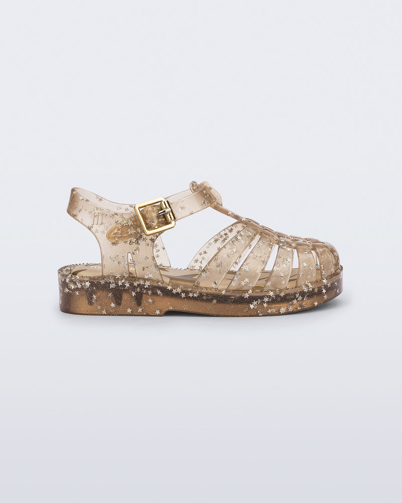 Side view of a clear beige Possession baby sandal with star glitter