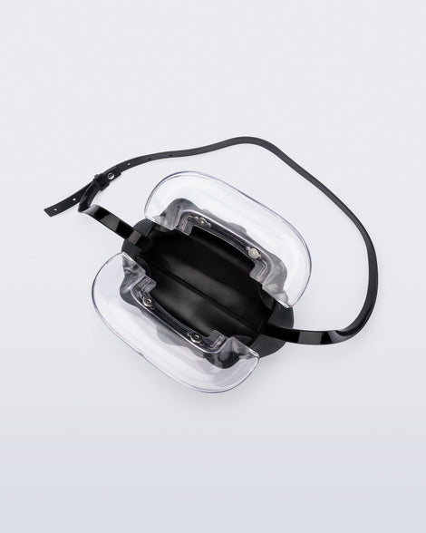Top view of a small black bag with clear clutch and long strap