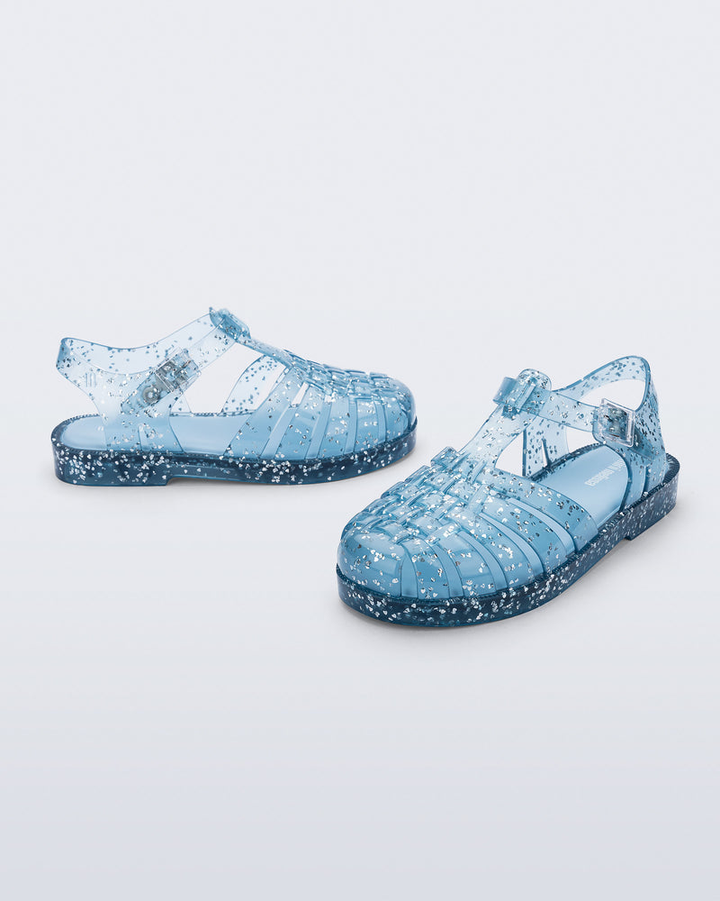 Side and angled view of a pair of blue Possession kids sandals with heart glitter