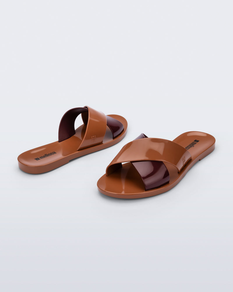 Back and angled view of a pair of brown Essential Cross Slide sandals
