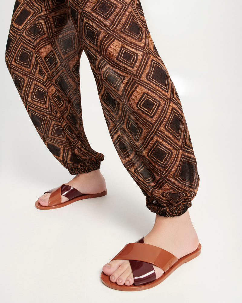 Models legs wearing a pair of brown Essential Cross Slide sandals