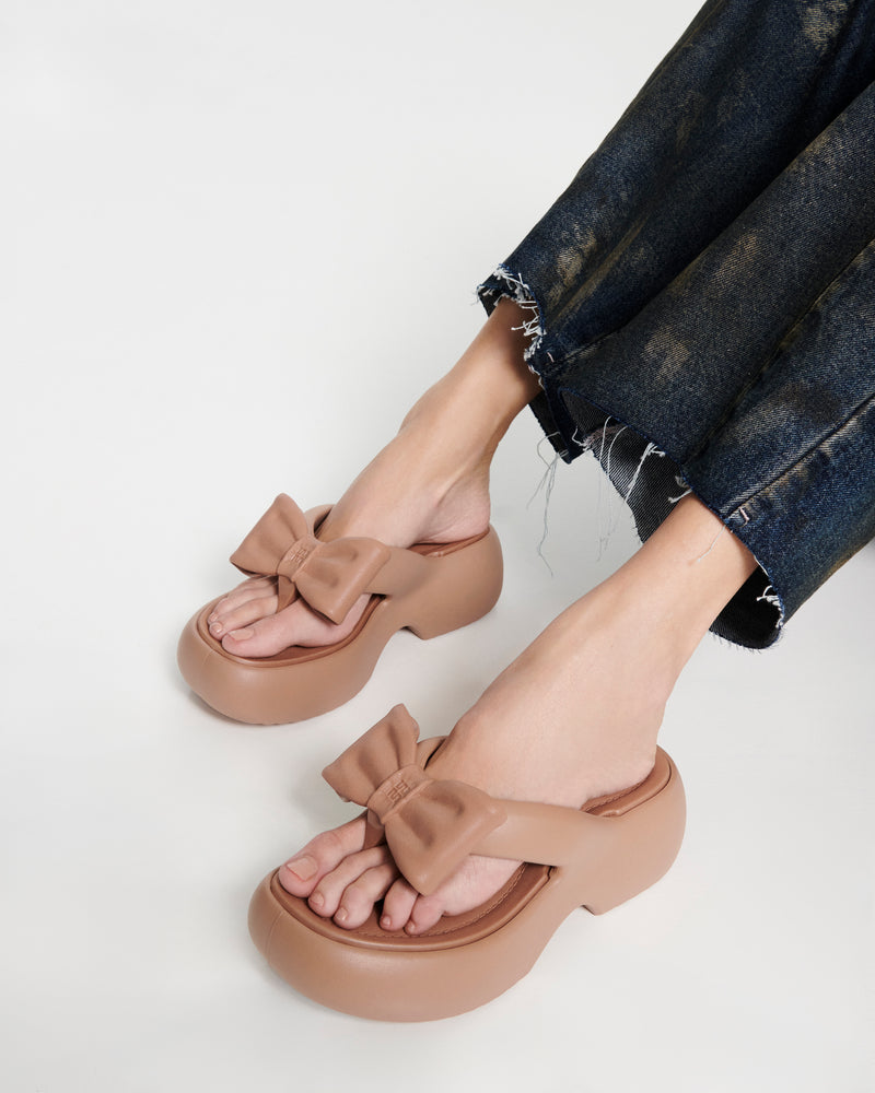 Model's legs wearing a pair of brown Free Fuzzy Platform flip flops