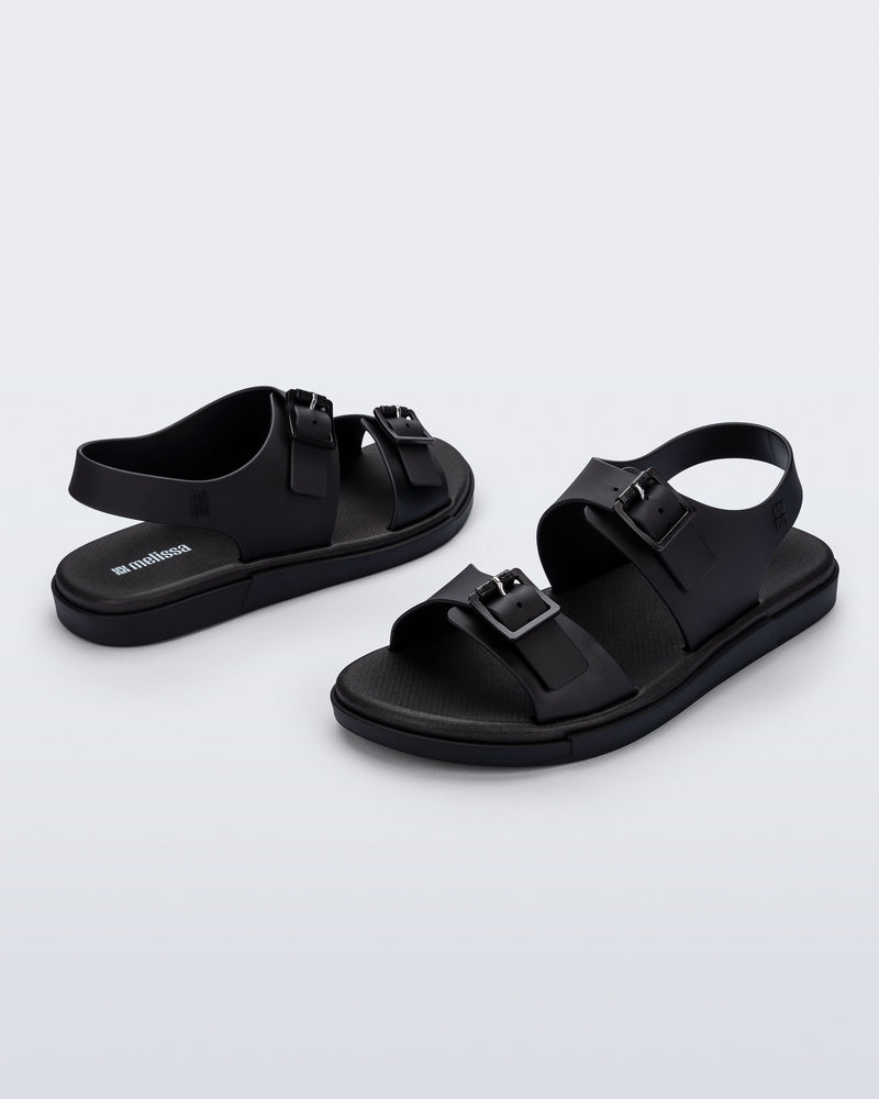 Side and angled view of a pair of black Wave Sandals with two straps with buckles and a back strap