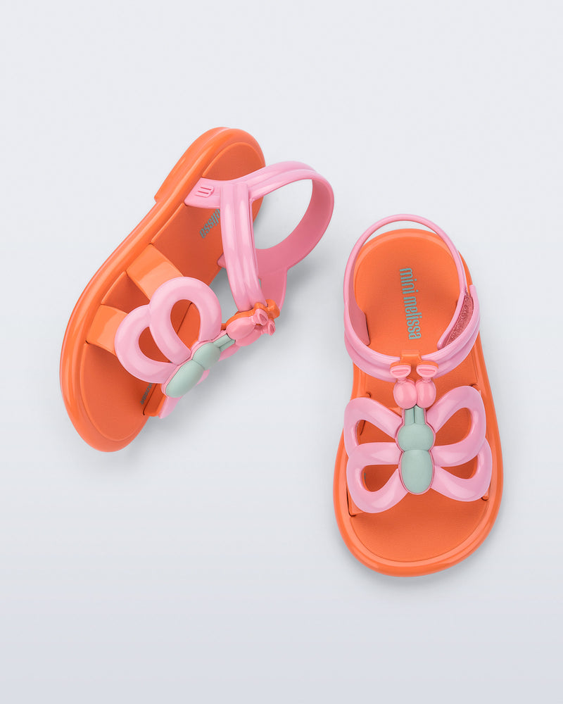 Side and angled view of a pair of pink strap, orange sole Hip Butterfly baby sandals