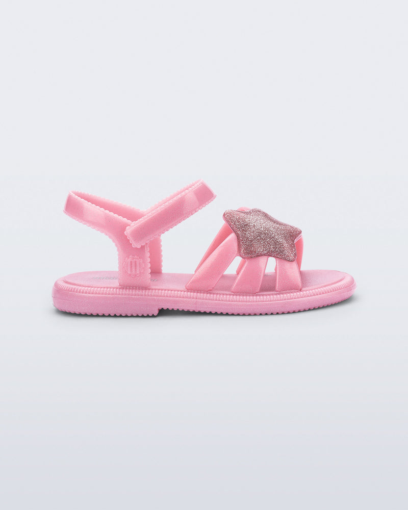 Side view of a pearly pink Hip Sky baby sandal with a glitter pink star on top