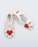 Side and top view of a pair of white Hip Heart Ballerina baby sandals with red heart on front