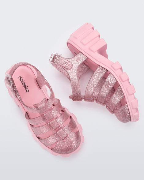 Side and top view of a pair of glitter pink Megan kids heel sandals.
