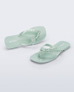 Side and angled view of a pair of green Harmonic Squared flip flops with bow on strap