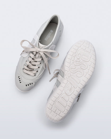Top and bottom view of a pair of grey Motion sneakers with white colored sole and M monogram on side