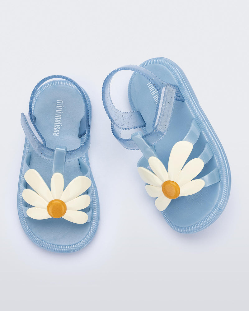 Top view of a pair of metallic blue Hip Bloomy baby sandals with beige daisy on top