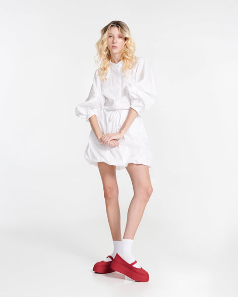 Model in a white dress wearing a pair of red Soft Ballerina Platform flats with white shocks