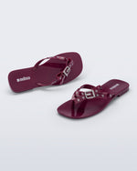 Side and angled view of a pair of red Harmonic Squared flip flops with bow on strap