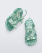 Side and top view of a pair of pearly green baby Dream Sandal with two bows and gold detail on strap