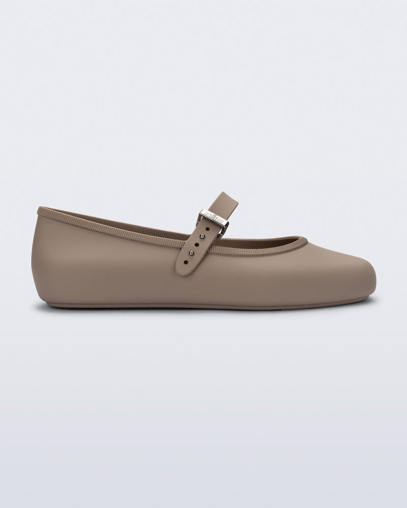 Side view of a dark beige Soft Ballerina flat with top buckle strap