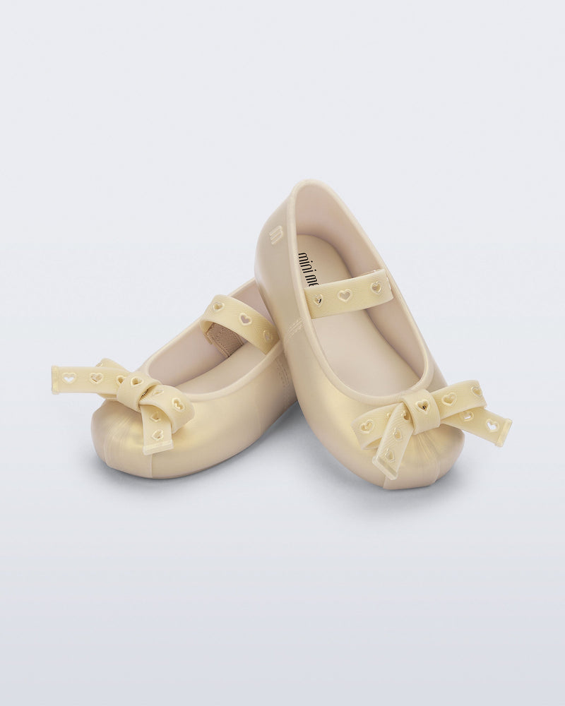 Angled view of a pair of pearly beige Sophie Crush baby ballerina flats with bow