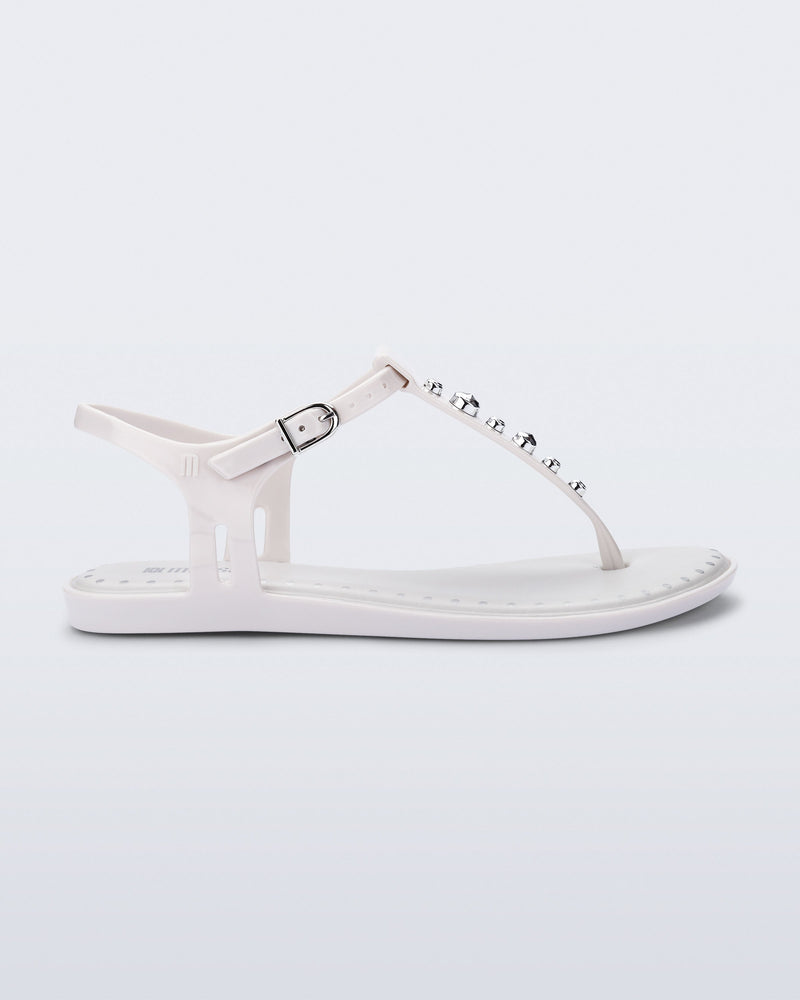 Side view of a white Solar Boho t-strap sandal with ,metallic detailing on the front strap