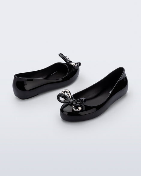 Angled and side view of a pair of black Sweet Love Glam kids ballerina flats with bow