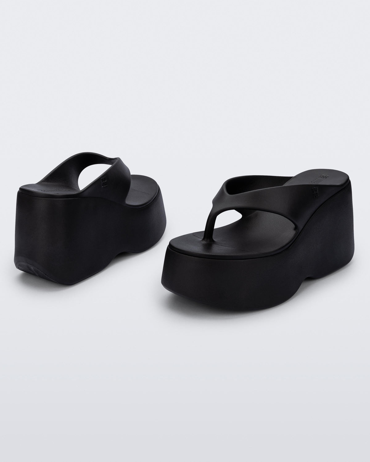 Back and angled view of a pair of black Free Thong Wedge Platform heels