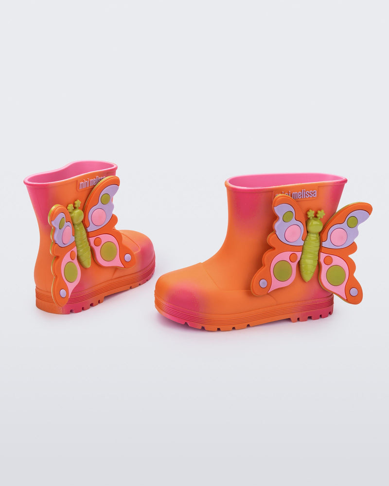 back and side view of a pair of orange with pink splotches Welly Wonderland baby boot with orange/green butterfly on side