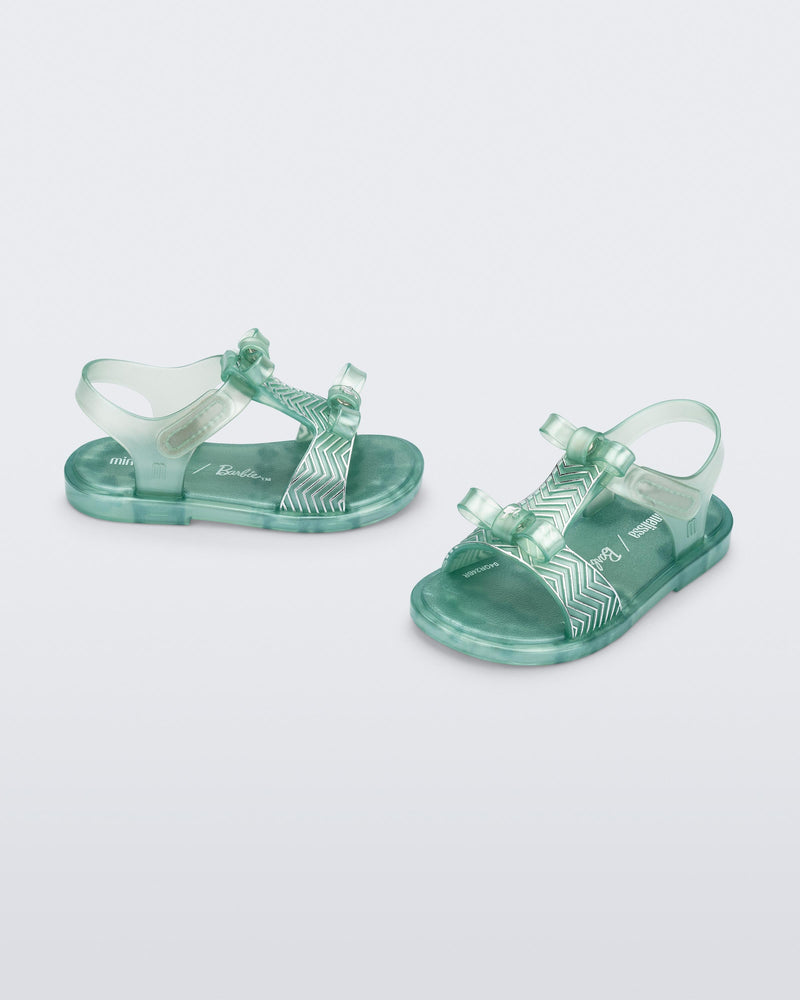 Side and angled view of a pair of pearly green baby Dream Sandal with two bows and gold detail on strap