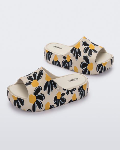 Angled view of a pair of beige Free Print Platform slides with a black and yellow flower print.