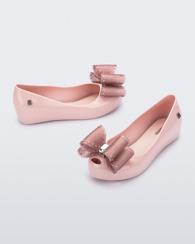 Side and angled view of a pair of light pink Ultragirl Classic Bow kids flats with glitter pink bow on top