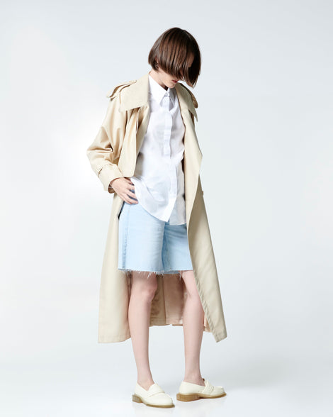 Model in white button down, beige rain coat and jean shorts wearing a pair of beige Spencer loafers with clear beige soles